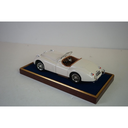 1169 - Five cased 1:18 scale diecast model classic cars to include BMW, Jaguar etc, models fixed to a woode... 