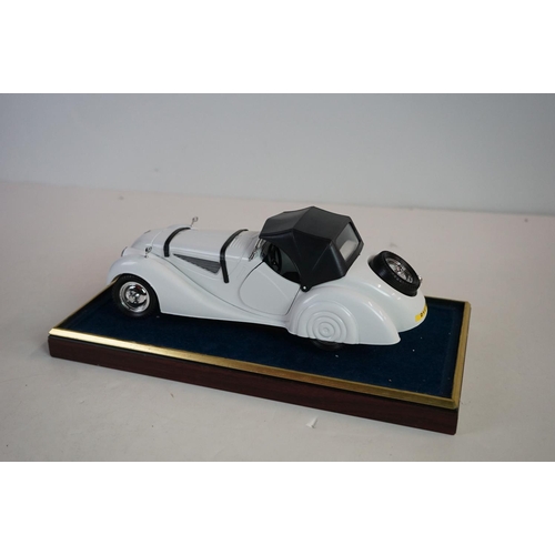 1169 - Five cased 1:18 scale diecast model classic cars to include BMW, Jaguar etc, models fixed to a woode... 