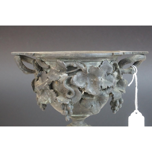 115 - A 19th century bronze two handled cup profusely decorated with grape vines mounted on a stone base p... 