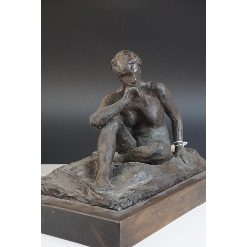 130 - Contemporary sculpture of a seated naked woman raised on a wooden plinth by Ivor Plummer, 31cms long