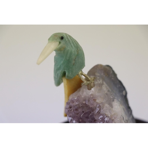 200 - A small carved stone bird mounted on a crystal base on a wooden plinth.