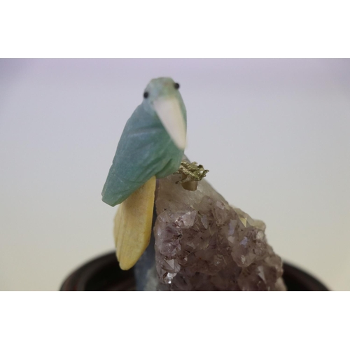 200 - A small carved stone bird mounted on a crystal base on a wooden plinth.