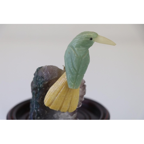 200 - A small carved stone bird mounted on a crystal base on a wooden plinth.