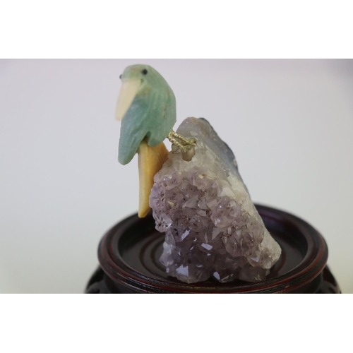 200 - A small carved stone bird mounted on a crystal base on a wooden plinth.