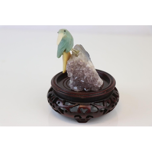 200 - A small carved stone bird mounted on a crystal base on a wooden plinth.