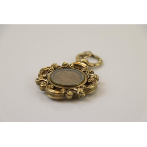 298 - Victorian yellow metal fob, the glazed central panel containing hair, engine turned reverse with sma... 