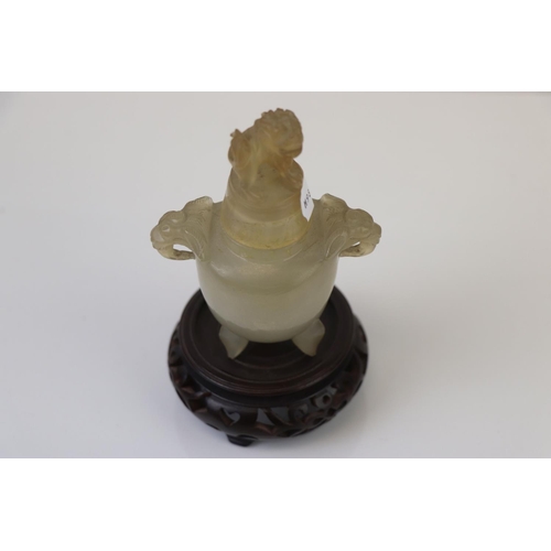 337 - An oriental carved Jadeite lidded urn with Foo dog to the lid and hardwood base.