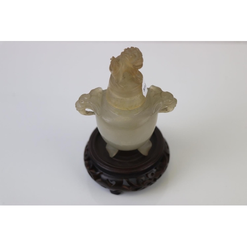 337 - An oriental carved Jadeite lidded urn with Foo dog to the lid and hardwood base.