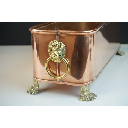 46 - Copper Rectangular Planter with Brass Lion Mask Ring Handles and raised on four brass lion paw feet,... 