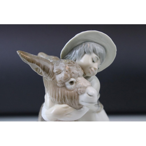 14 - A Lladro figure of a Young boy cuddling a donkey.