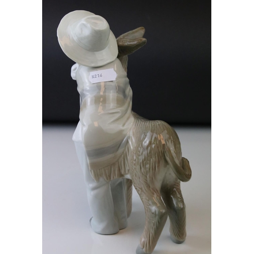 14 - A Lladro figure of a Young boy cuddling a donkey.