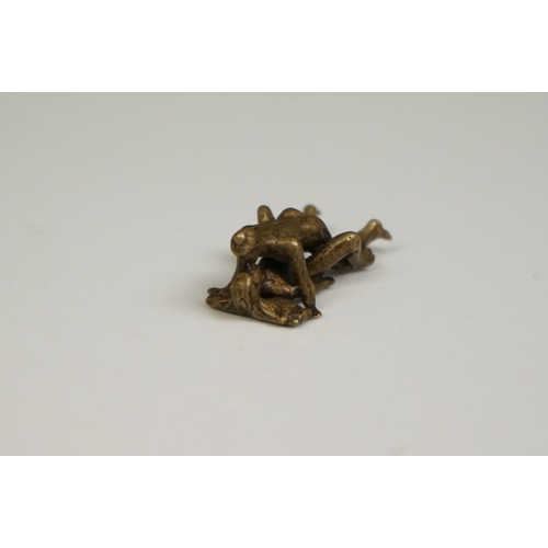 175 - A miniature brass figure of an erotic couple.