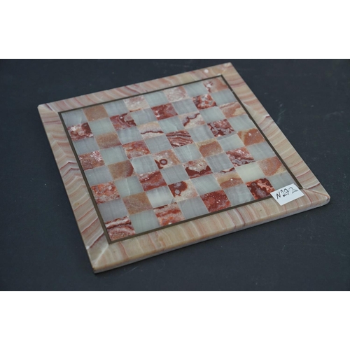 212 - A wooden solitaire board complete with vintage marbles together with an agate chess board.