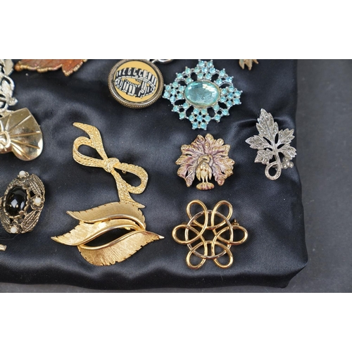 219 - A collection of over thirty brooches and pin badges.