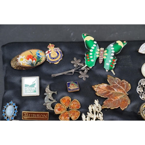 219 - A collection of over thirty brooches and pin badges.