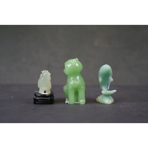 282 - A collection of three oriental carved jade animals to include a cat, dolphin and a cockerel on woode... 