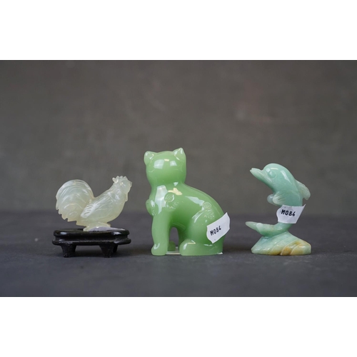 282 - A collection of three oriental carved jade animals to include a cat, dolphin and a cockerel on woode... 