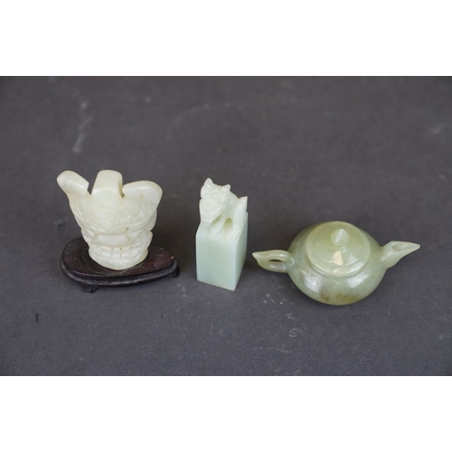 300 - A small collection of three oriental carved Jade ornaments to include a teapot, a seal and a mask on... 