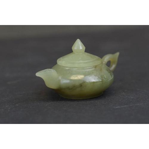 300 - A small collection of three oriental carved Jade ornaments to include a teapot, a seal and a mask on... 