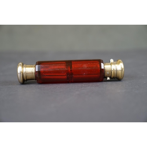 302 - A vintage Ruby glass double ended scent bottle, two brass tops with one being spring loaded.