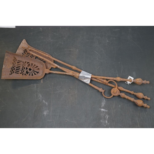 506 - A vintage iron three piece fire tool companion set comprising of two shovels and a pair of tongs.