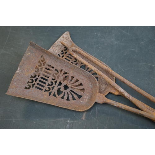 506 - A vintage iron three piece fire tool companion set comprising of two shovels and a pair of tongs.