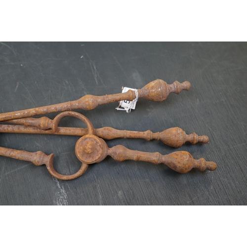 506 - A vintage iron three piece fire tool companion set comprising of two shovels and a pair of tongs.