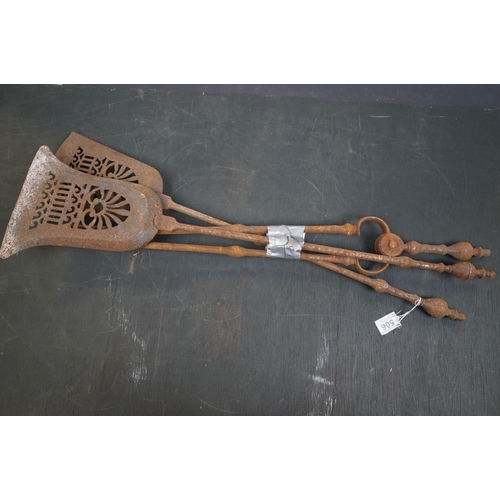 506 - A vintage iron three piece fire tool companion set comprising of two shovels and a pair of tongs.