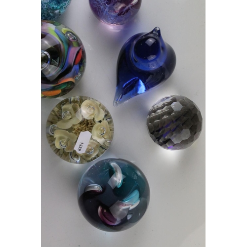 513 - A collection of seven glass paperweights to include Caithness examples.