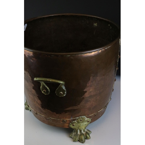 67 - A riveted copper coal bucket with brass lion feet together with another copper coal bucket.