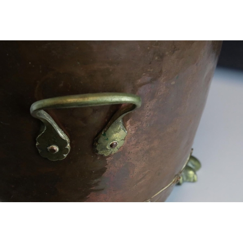 67 - A riveted copper coal bucket with brass lion feet together with another copper coal bucket.