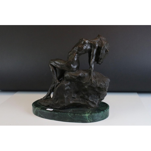 93 - Bronze figure of a nude woman reclining on a rock, on a green marble base