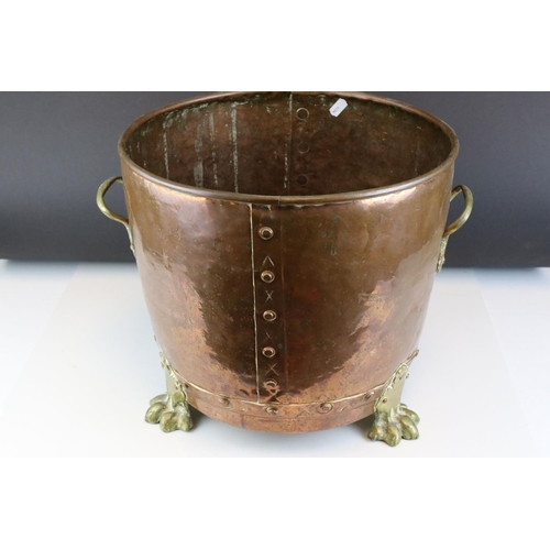 67 - A riveted copper coal bucket with brass lion feet together with another copper coal bucket.