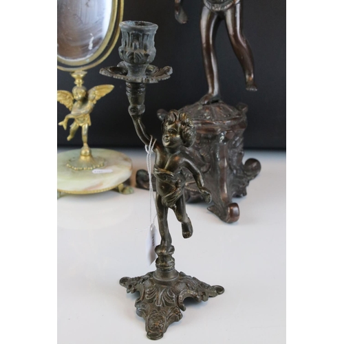 106 - Two bronzed cast metal candlesticks in the form of cherubs together with a mirror.