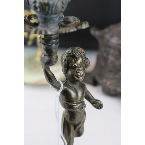 106 - Two bronzed cast metal candlesticks in the form of cherubs together with a mirror.