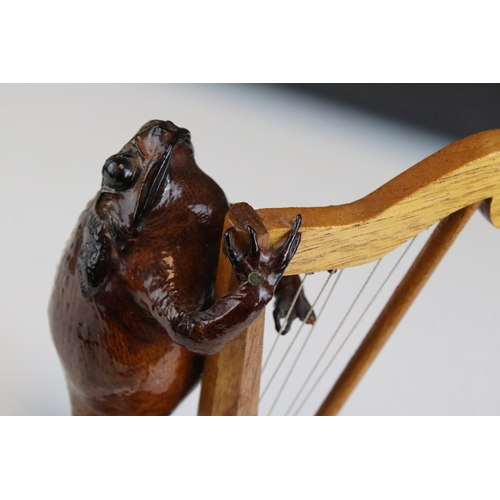 111 - A Taxidermy toad playing harp mounted to wooden stand.