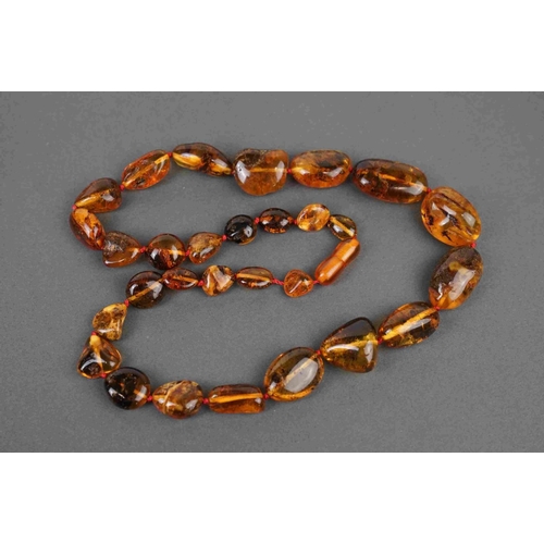 281 - A collection of four Amber style necklaces and a Amber style pendant on a yellow metal chain.