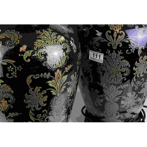 111 - A pair of  black ground contemporary lamps with stylized floral decoration.