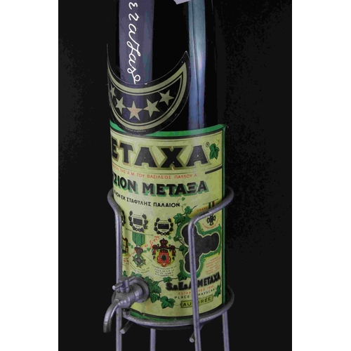 37 - Mid 20th century oversized Metaxa bottle with tap on a Metal stand, 77cms high