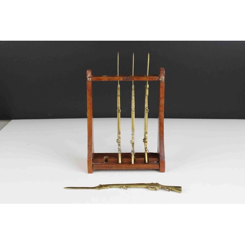 63 - Four Trench Art Brass Desk Paperknives in the form of  Rifles contained within a wooden gun rack, 20... 