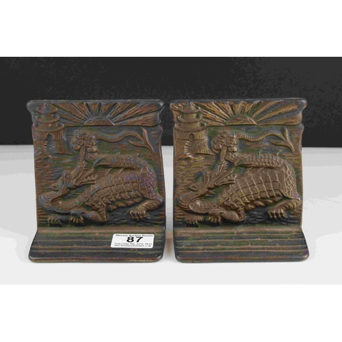 87 - A pair of oriental style bronze bookends with dragon decoration, registration mark to reverse.