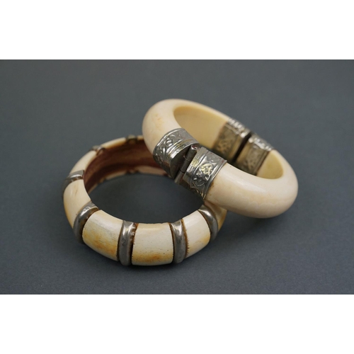 343 - Two vintage bone / tusk bangles with white metal fittings.