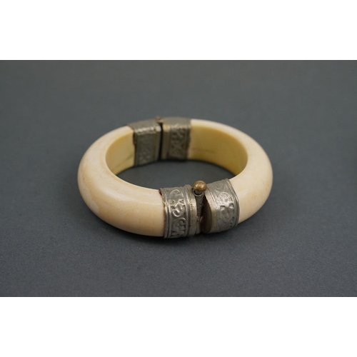 343 - Two vintage bone / tusk bangles with white metal fittings.