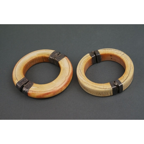 344 - Two vintage bone / tusk bangles with white metal fittings.