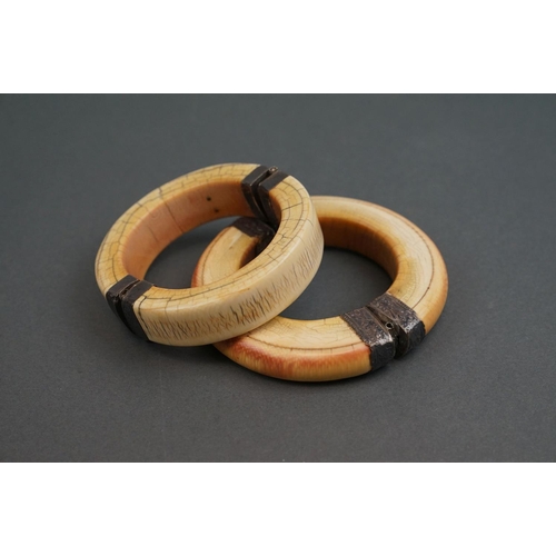 344 - Two vintage bone / tusk bangles with white metal fittings.