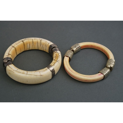 345 - Two vintage bone / tusk bangles with white metal fittings.