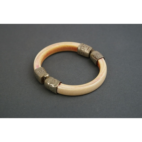 345 - Two vintage bone / tusk bangles with white metal fittings.