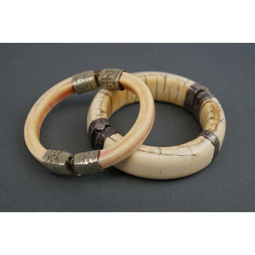 345 - Two vintage bone / tusk bangles with white metal fittings.