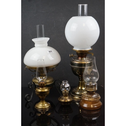 488 - A collection of five oil lamps to include four brass examples.