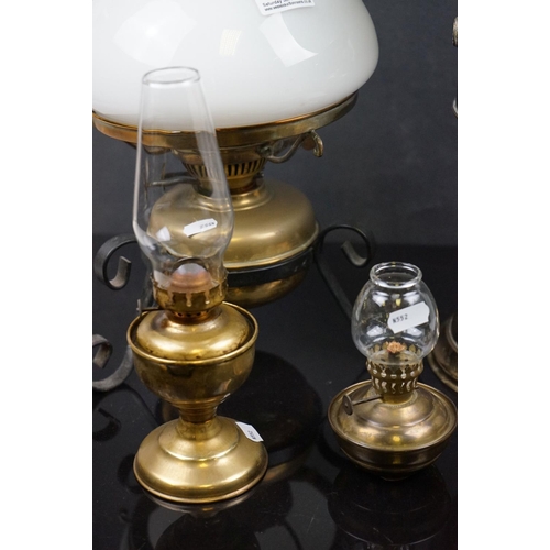 488 - A collection of five oil lamps to include four brass examples.